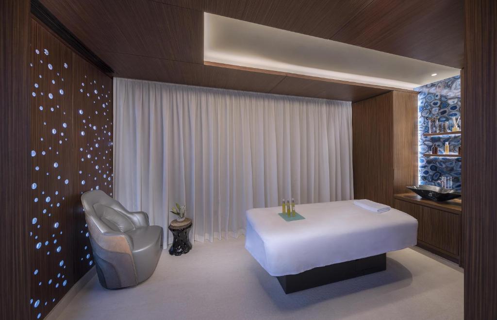 Andaz Dubai The Palm spa telpa ar masāžas galdu un atpūtas krēslu.