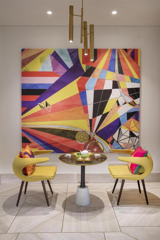 Krāsains mākslas darbs Andaz Dubai The Palm viesnīcā ar modernu mēbeļu komplektu.