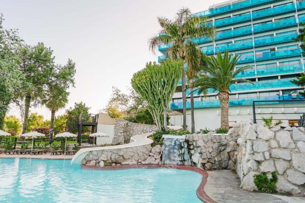 Kalypso Beach viesnīcas baseins ar slidkalniņu un palmu kokiem