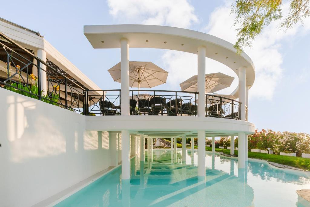 Kalypso Beach viesnīcas baseins ar terasi un saules aizsargiem piekrastē.