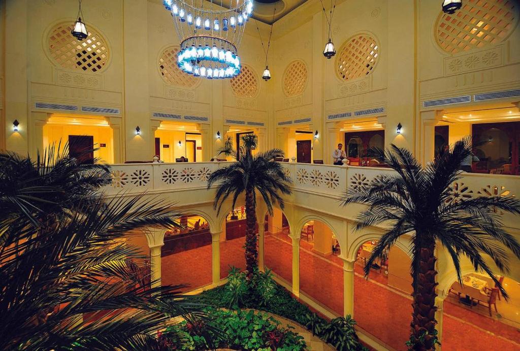 Baron Palms Resort elegantais interjers ar palmām un greznām lampām.