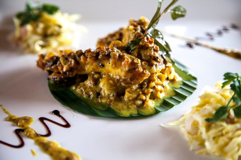 Gardīgs ēdiens uz lapas, kas pasniegts ar krēmīgu mērci un garšaugiem, blakus ir dārzeņu salāti.