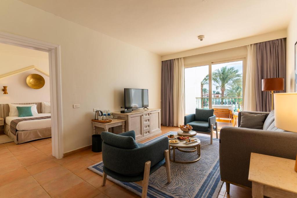 Mūsdienīgs viesnīcas numurs ar dzīvojamo telpu un skatu uz palmu dārzu, Baron Palms Resort.