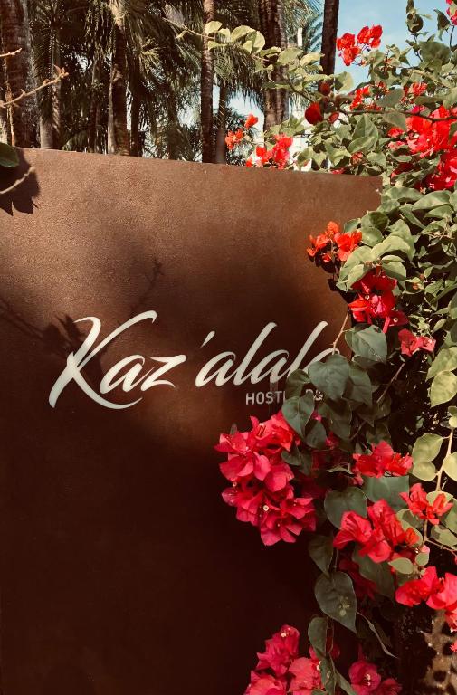 Kaz'alala Hosted B&B zīme ar ziediem apkārt