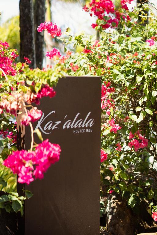 Kaz'alala Hosted B&B zīme ar ziediem apkārt