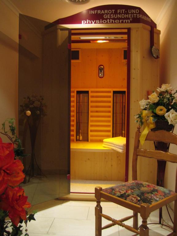 Infrasarkano staru sauna ar koka interjeru un ziedu kompozīciju tuvumā. Gaisma rada relaksējošu atmosfēru.