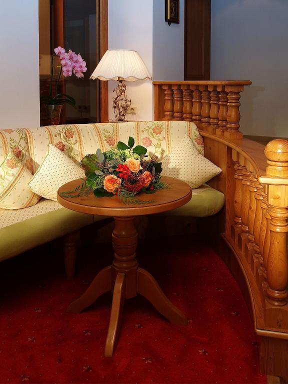 Skaista viesistaba ar dīvānu, dekoratīvajām spilveniem un mazu galdiņu, uz kura atrodas ziedu kompozīcija. Interjers izstaro mājīgumu un eleganci.