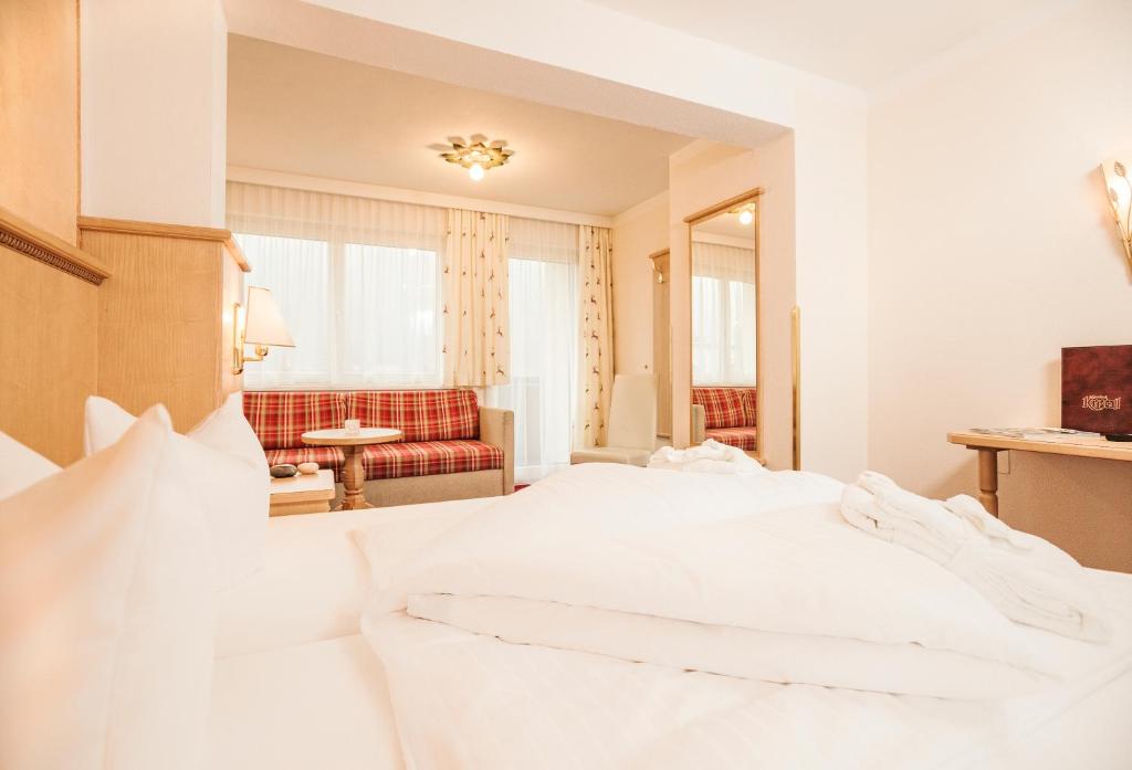 Mūsdienīga viesnīcas istaba ar ērtiem gultas piederumiem un atpūtas zonu, kurā ir dīvāns un galdiņš. Labi apgaismota telpa ar logiem, kas nodrošina dabisko gaismu.