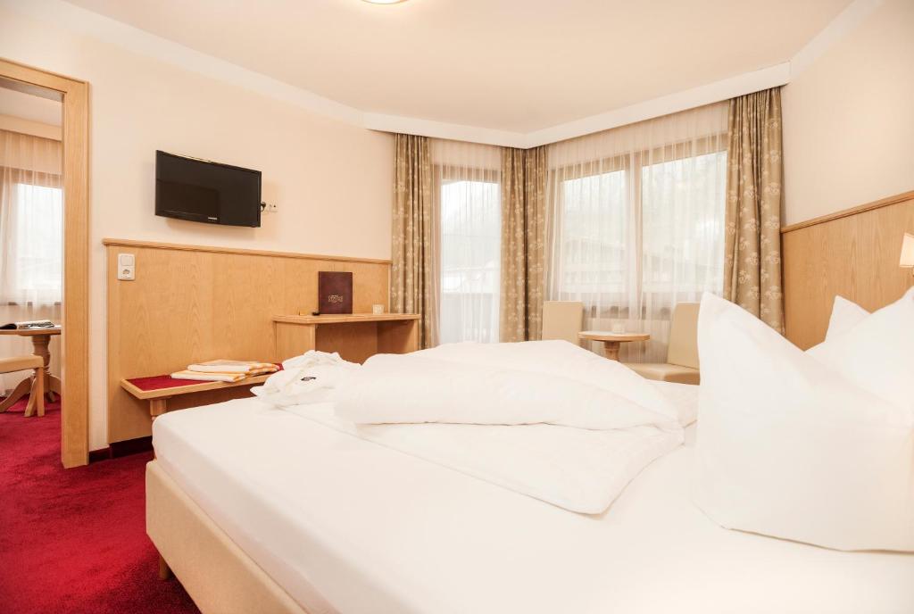 Mūsdienīgs viesnīcas numurs ar ērtu gultu, televizoru un dabīgu apgaismojumu, kas ieplūst caur lielajiem logiem. Interjers ir veidots ar neitrālām krāsām un dabīgiem materiāliem, radot patīkamu atmosfēru.