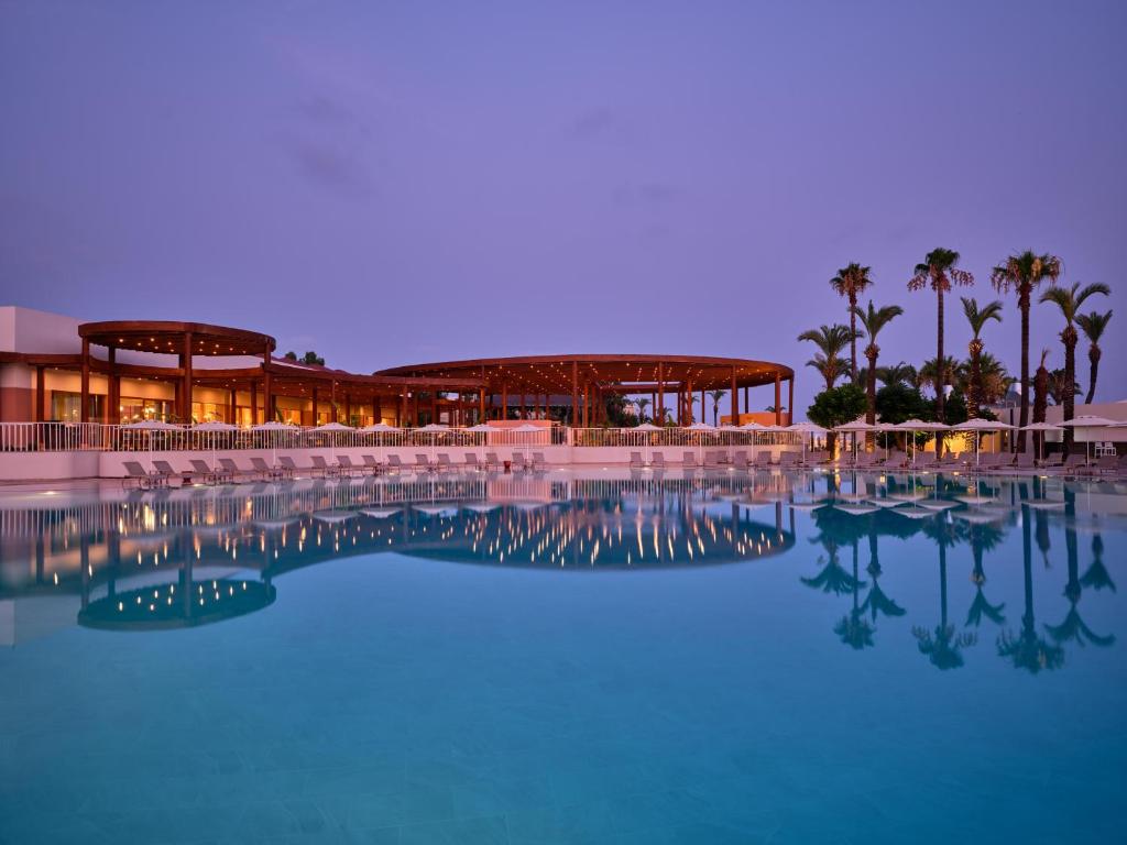 Paloma Grida viesnīca ar izgaismotu baseinu saulrietā