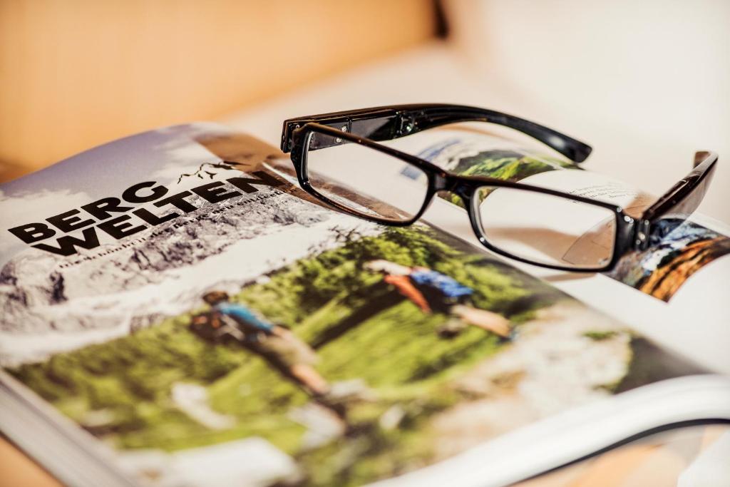 Aplūkojot žurnālu "Bergwelten" ar brillēm, kas novietotas uz tā lapām, attēls izsaka ceļojumu un dabas izpēti.