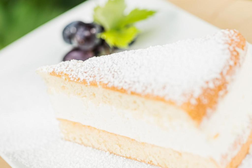 Gaisīgs kūkas gabals ar pūdercukuru, blakus mellenēm un svaigu zaļumu. Ideāls deserts ikdienai vai svinībām.