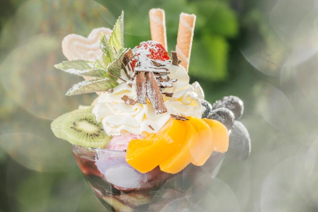 Saldējuma desertu kompozīcija ar augļiem, putukrējumu un dekoratīviem saldumiem. Krāsains un pievilcīgs deserts, ideāls vasaras uzkodu baudi.