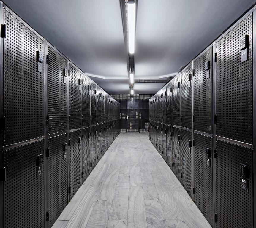 Mūsdienīga, melna skapi telpa ar metāla plauktiem un minimālu apgaismojumu, kas rada modernu un stilīgu atmosfēru.