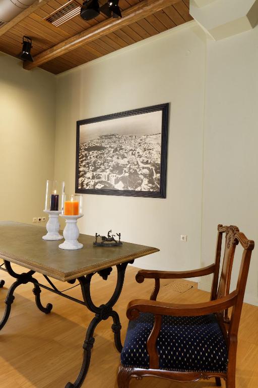 Vietā ar elegantu galdu un krēslu, pie kura atrodas sveces un melnbalta fotogrāfija uz sienas.