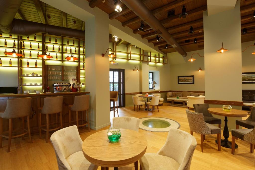 Mūsdienīgs bārs ar elegantu interjeru, kas ietver koka apdari un mīkstus krēslus, radot patīkamu atmosfēru atpūtai. Apgaismojums un dekorācijas piešķir telpai siltumu un komfortu.