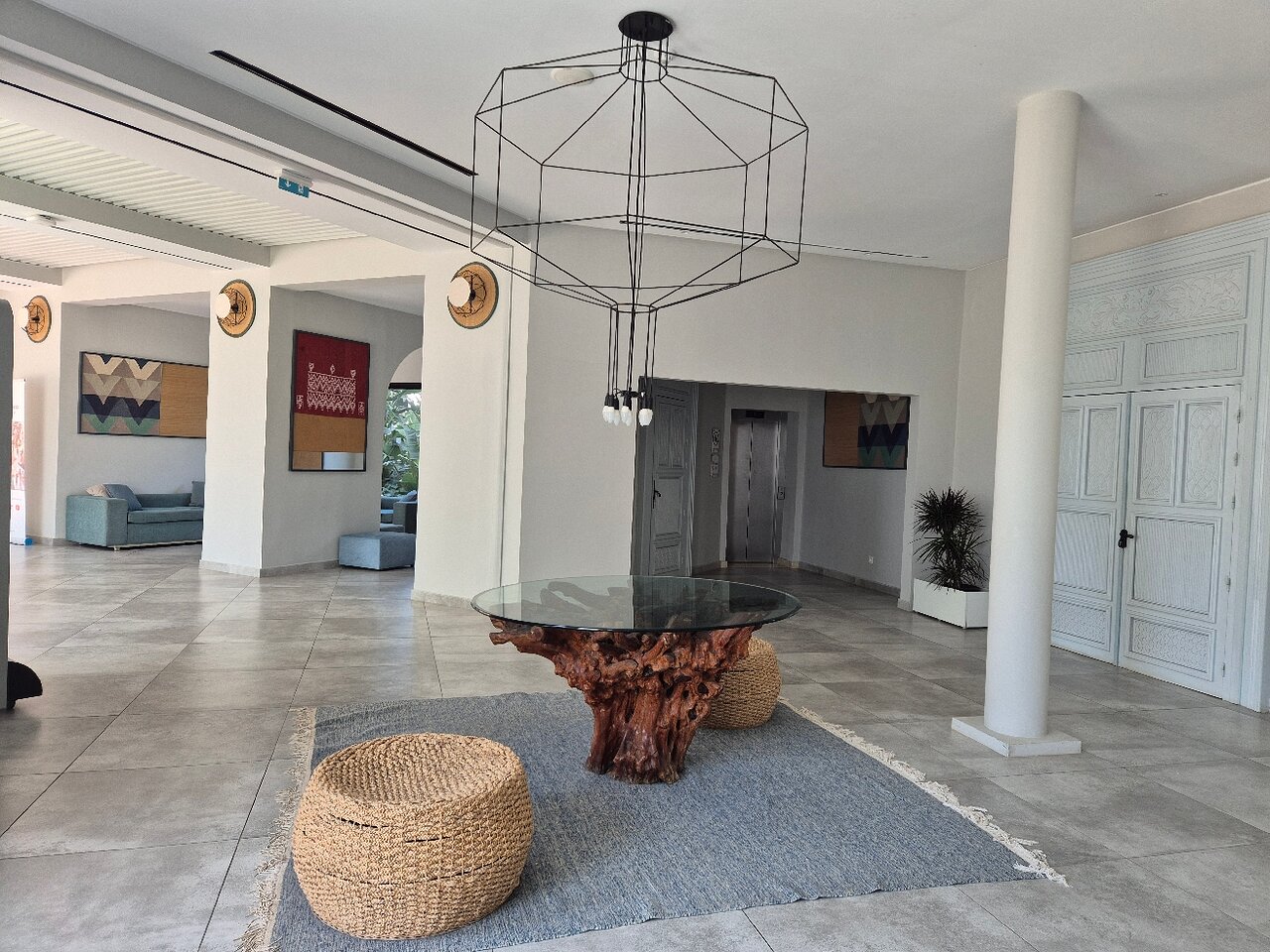 Moderns interjers ar elegantu stikla galdu, dabīgā koka bāzi un rattan mēbelēm, radot mājīgu un stilīgu atmosfēru. Sienas rotā mākslas darbi un dekoratīvi elementi. panoramic view with beach and pools