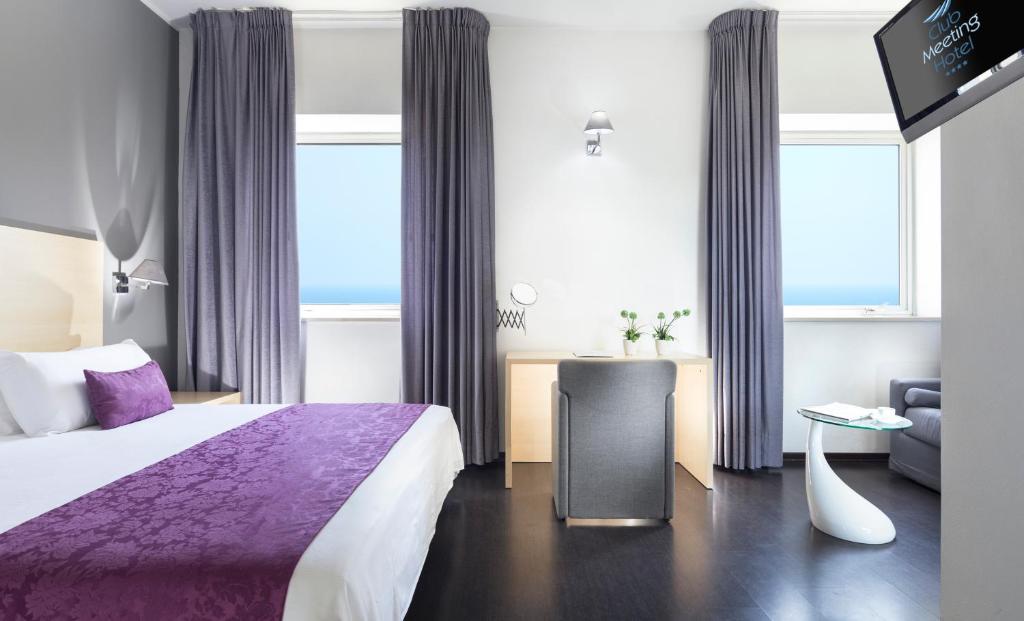 Mūsdienīga viesnīcas numura interjers ar ērtu gultu, darba galdu un skatu uz jūru. Telpā ir gaišas krāsas un eleganti dekori.