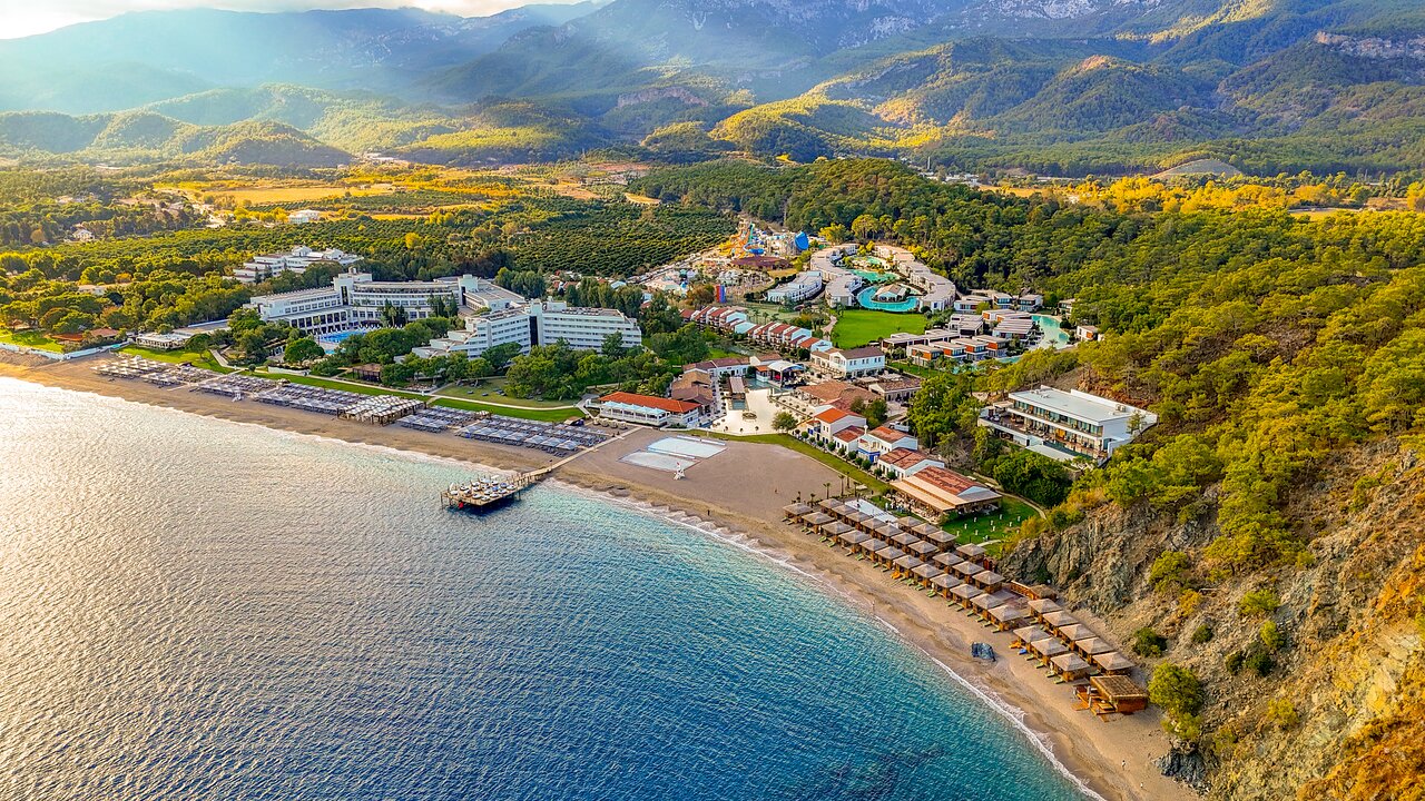 Kūrorta zona pie jūras ar viesnīcām un pludmali, ieskauta kalnos un zaļumos. Šī ainava piedāvā relaksējošu atmosfēru un skaistus skatus. panoramic view with beach and pools