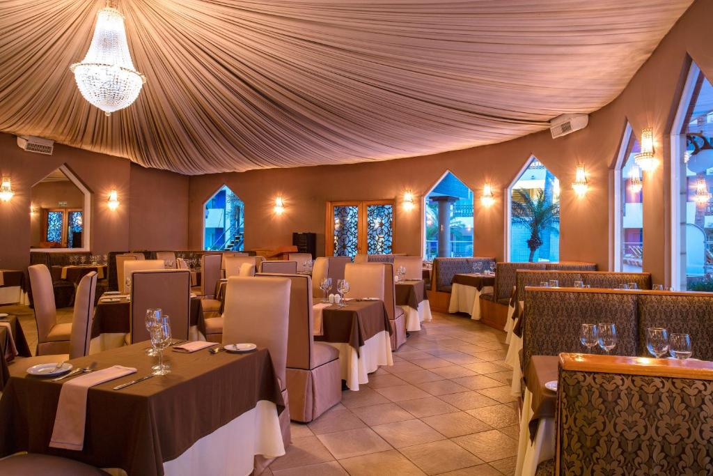 Elegants restorāns ar izsmalcinātu interjeru, kurā ir mīkstas krēslas un skaista apgaismojuma dizains. Telpa ir dekorēta ar drapērijām un logiem, kas piedāvā skatu uz ārpusi.