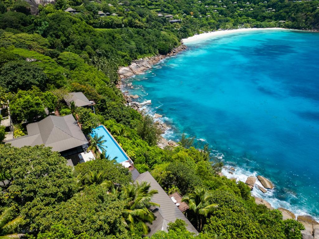 Four Seasons Resort Seychelles villas ar privātiem baseiniem, kas ieskautas tropu zaļumos piekrastē.