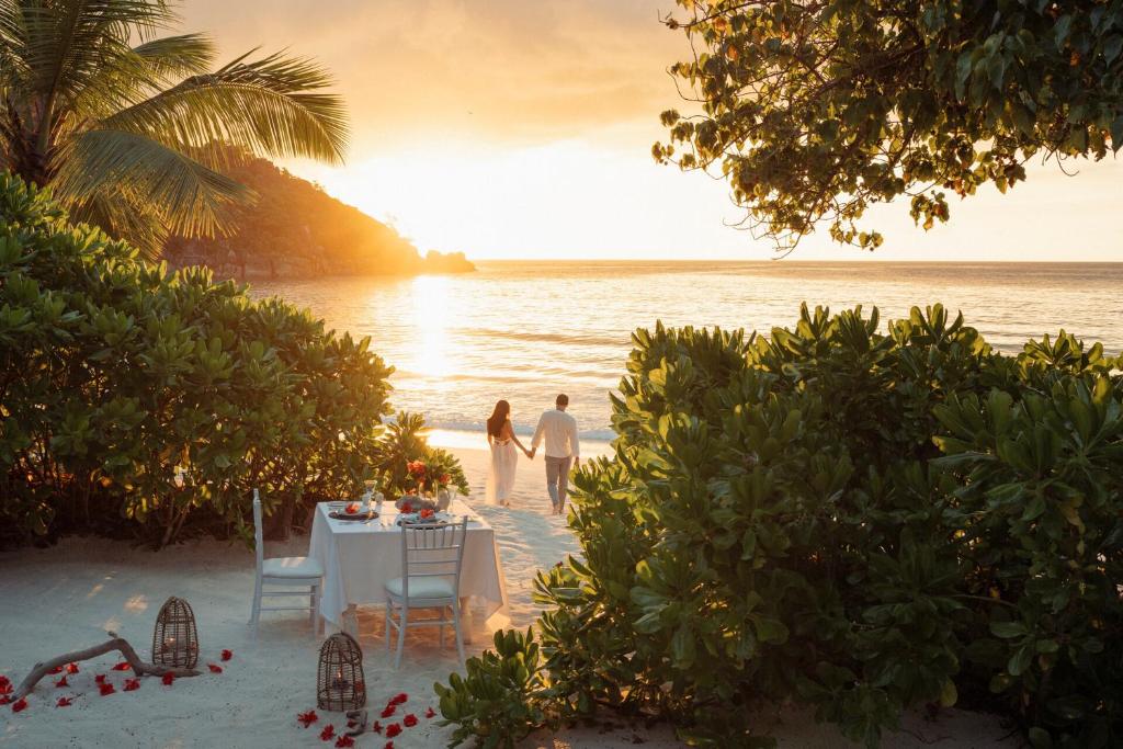 Four Seasons Resort Seychelles romantiskas vakariņas pludmalē saulrieta gaismā ar pāri piekrastē