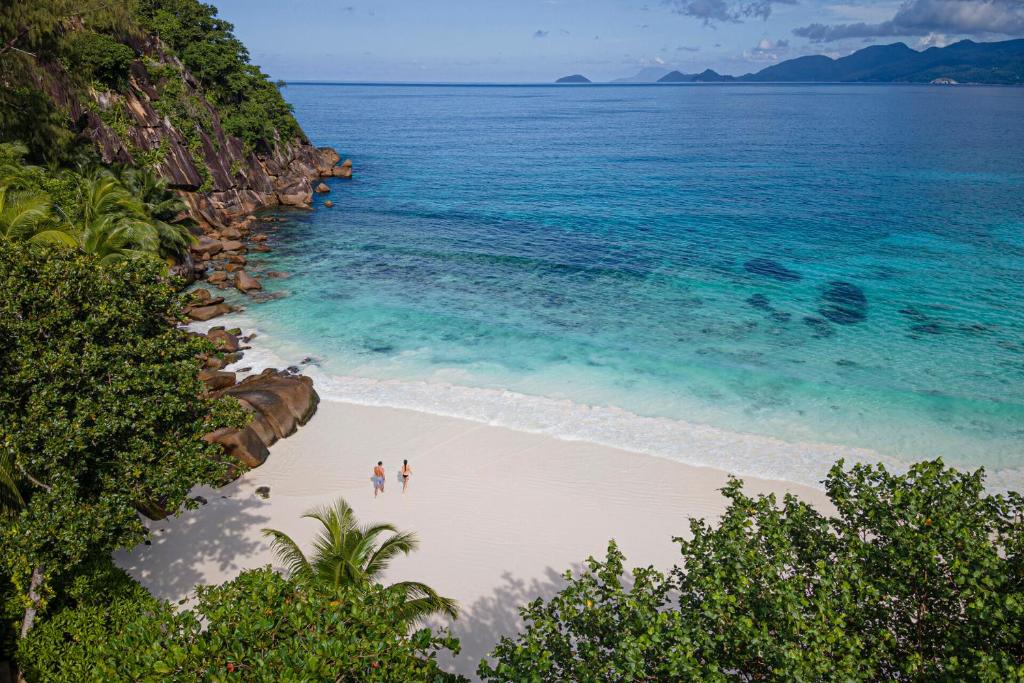 Four Seasons Resort Seychelles privātā pludmale ar balto smilšu krastu un tirkīzzilu okeānu.