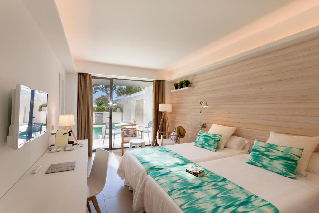 Mūsdienīgs viesnīcas numurs ar divām gultām, modernu interjeru un lielu logu, kas ved uz terasi ar skatu uz baseinu. Eleganti aksesuāri un gaismas piešķir telpai patīkamu atmosfēru.