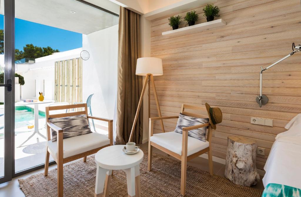 Mūsdienīgs un elegants interjers ar koka sienu un skatu uz baseinu. Divas ērtas krēsli un galds izveido patīkamu atpūtas stūri.