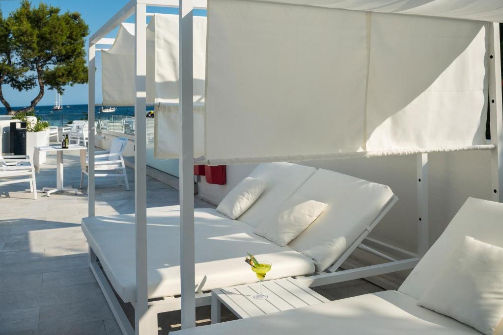 Atpūtas zona pie jūras ar baltām sauļošanās gultām un žogiem, kas nodrošina privātumu, kā arī galdiņu ar dzērienu. Ideāla vieta relaksācijai un saules baudīšanai.