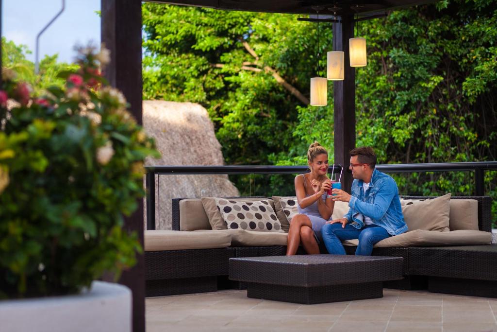 Skaista pāra brīvais laiks dārzā, baudot dzērienus uz komfortabla dīvāna. Apzaļumots fons rada relaksējošu atmosfēru.