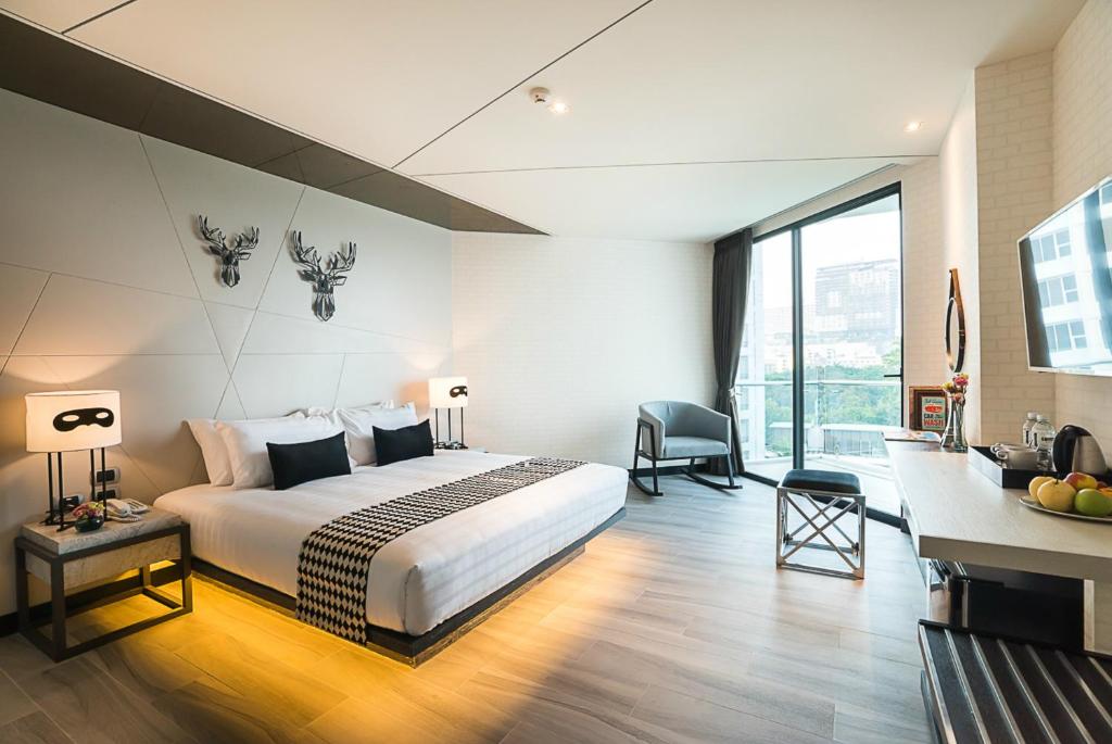 Mūsdienīgs viesnīcas numurs ar plašu gultu, dekoratīviem stāvu lampām un modernām mēbelēm. Lielas logu sienas nodrošina dabīgu apgaismojumu un skatu uz ārpusi.