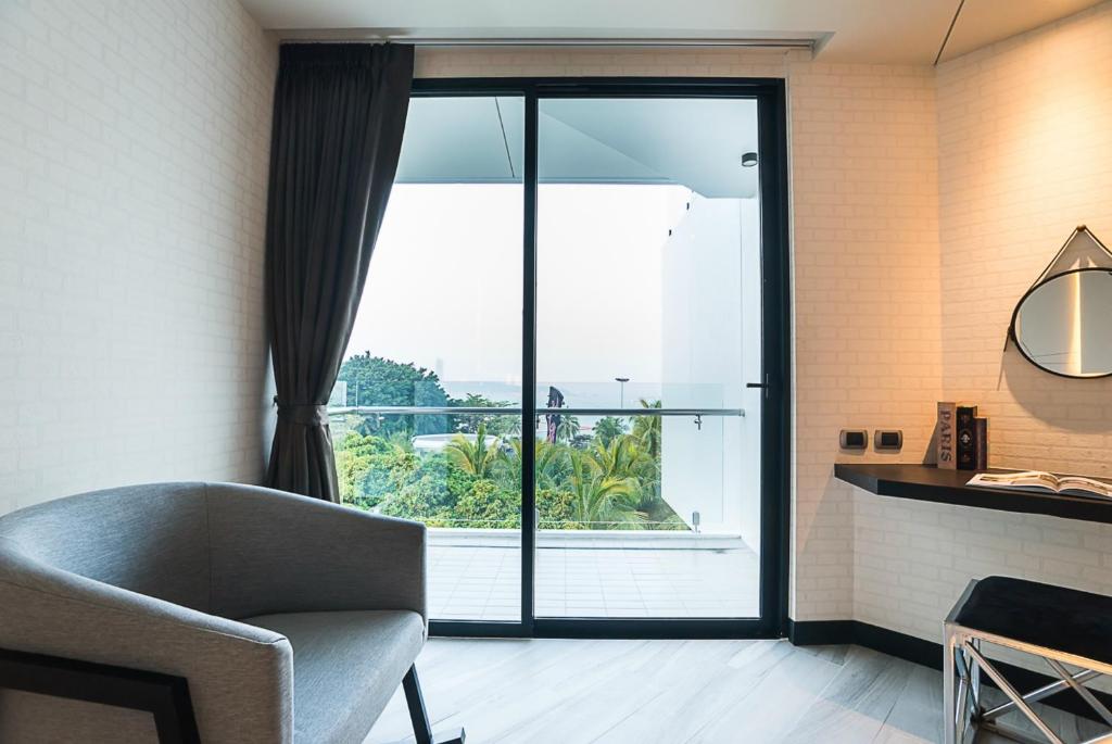 Gaiša un moderna telpa ar skatu uz dārzu caur lieliem stikla durvīm, iekārtota ar pelēku krēslu un melnu rakstāmgaldu.