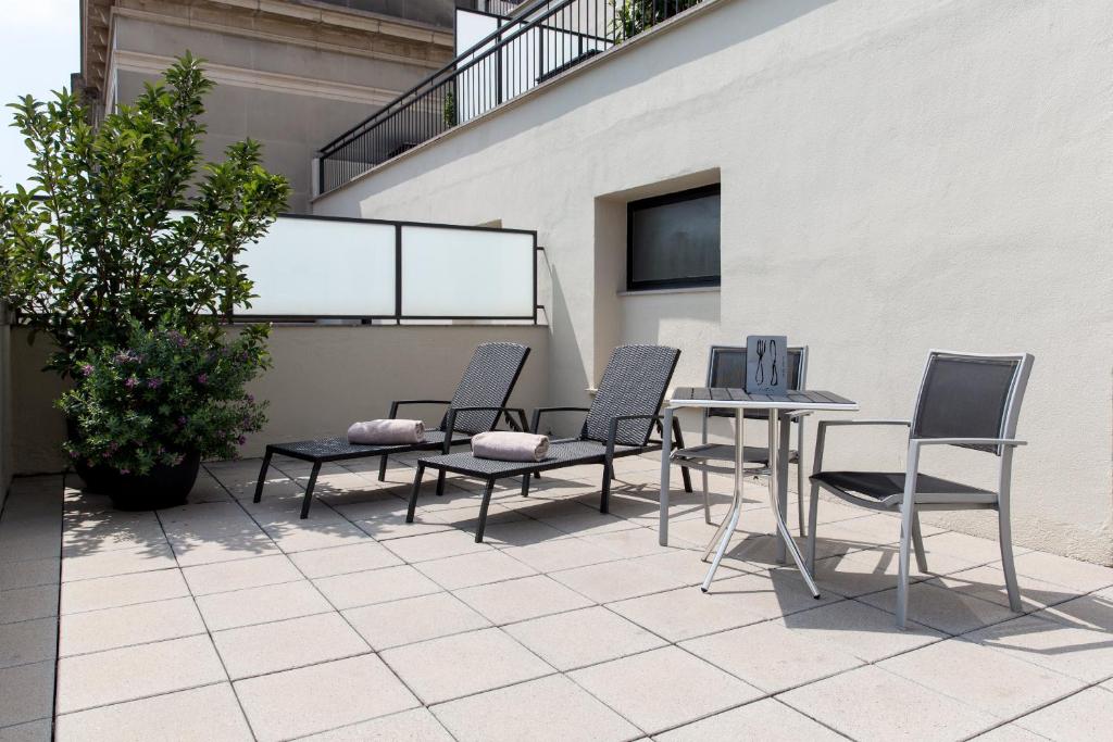 Terases zona ar četrām atpūtas krēslām, galdu un zaļām augu kompozīcijām, radot mierīgu un relaksējošu atmosfēru.