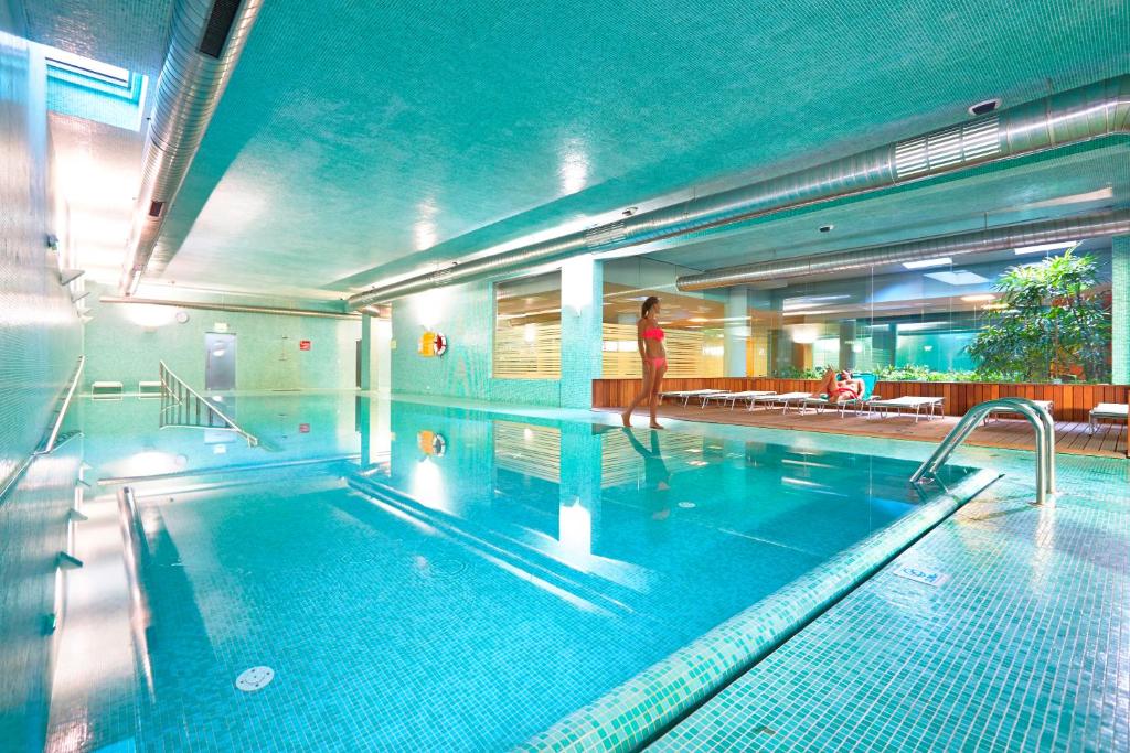 Iekštelpu peldbaseins ar mirdzošu ūdeni un modernu dizainu, ap kuru atrodas atpūtas zonas un zaļumi. Perfects relaksācijai un atpūtai.