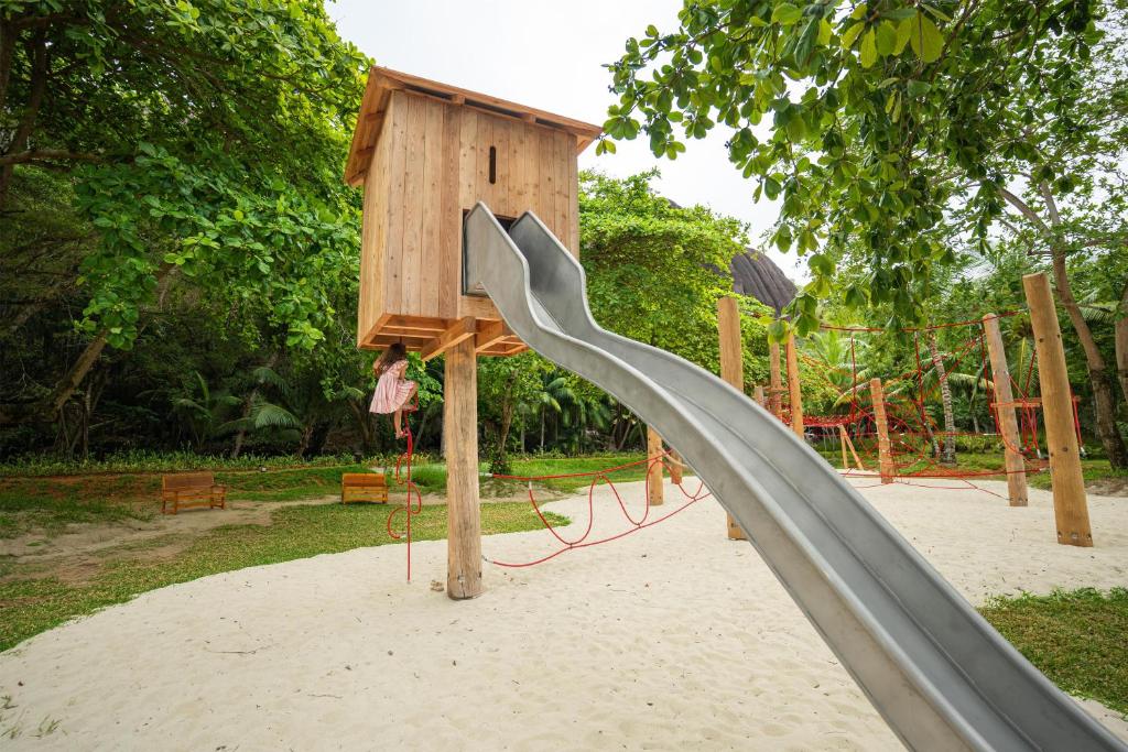 Kempinski Seychelles Resort bērnu rotaļu laukums ar koka namiņu un slidkalniņu.