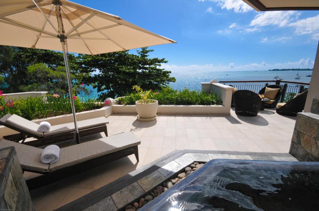 Terases zona ar saulessargu, guļamkrēsliem un skatu uz jūru, kur ziedi un zaļumi piešķir miera atmosfēru. Ideāla vieta relaksācijai pie ūdens.