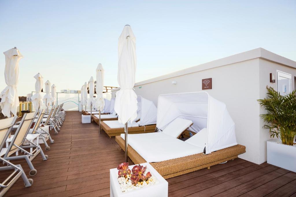 Terases zona ar sauļošanās gultām un baltām saulessargiem, kas piedāvā relaksējošu atmosfēru un brīnišķīgu skatu. Ideāla vieta atpūtai un komfortam.