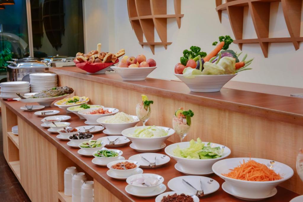 Bagātīga bufete ar dažādiem salātiem un dārzeņiem, kas izkārtoti uz koka galda. Redzamas arī zivis un deserti, radot pievilcīgu un daudzveidīgu ēdienu izvēli.