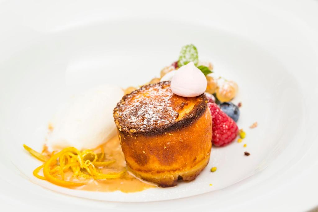 Saldais deserts ar kraukšķīgu virskārtu, pasniegts ar saldējumu un ogām, dekorēts ar piparmētru lapu un apelsīnu mizu.