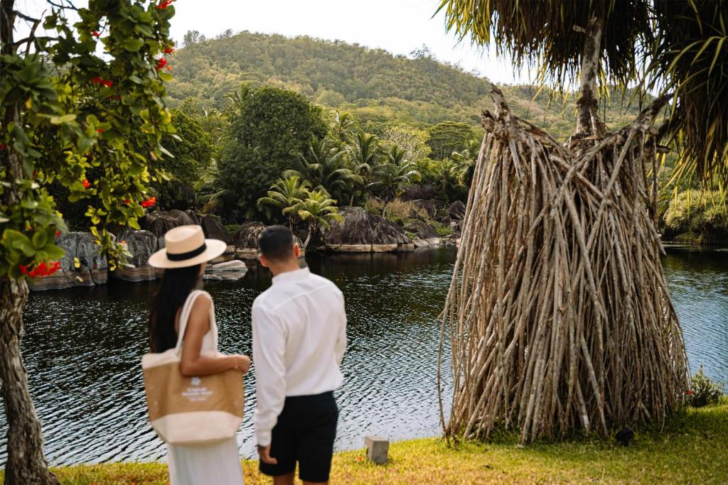 Pāris vēro tropisko lagūnu un kalnu ainavu Kempinski Seychelles Resort teritorijā