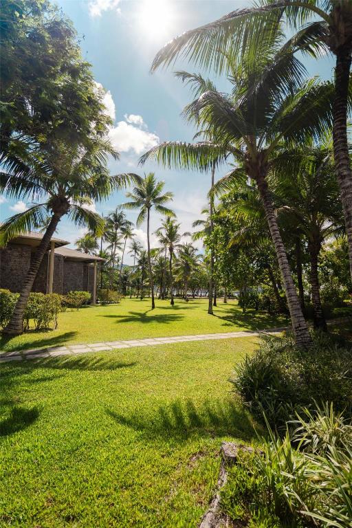 Kempinski Seychelles Resort tropiskais dārzs ar pastaigu taku un palmām saulainā dienā