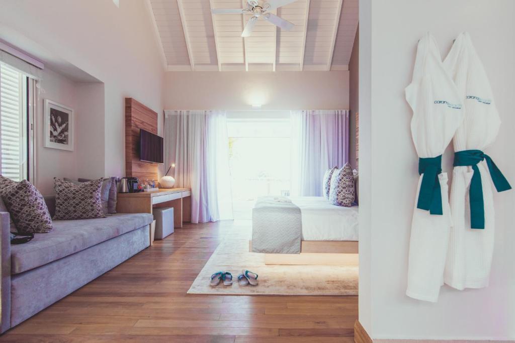 Mūsdienīgs viesnīcas numurs ar divām gultām, atpūtas stūri un plašām logu žalūzijām, kas nodrošina gaismu. Uz sienas redzamas divas baltas peldmēteļa kārtas ar zaļu jostu.