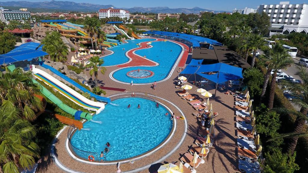 Vasaras izklaides komplekss ar ūdens slidām un peldbaseiniem, kur apmeklētāji izbauda sauli un ūdens aktivitātes. Apkārtējā ainava ir zaļa un tropiska, radot relaksējošu atmosfēru.