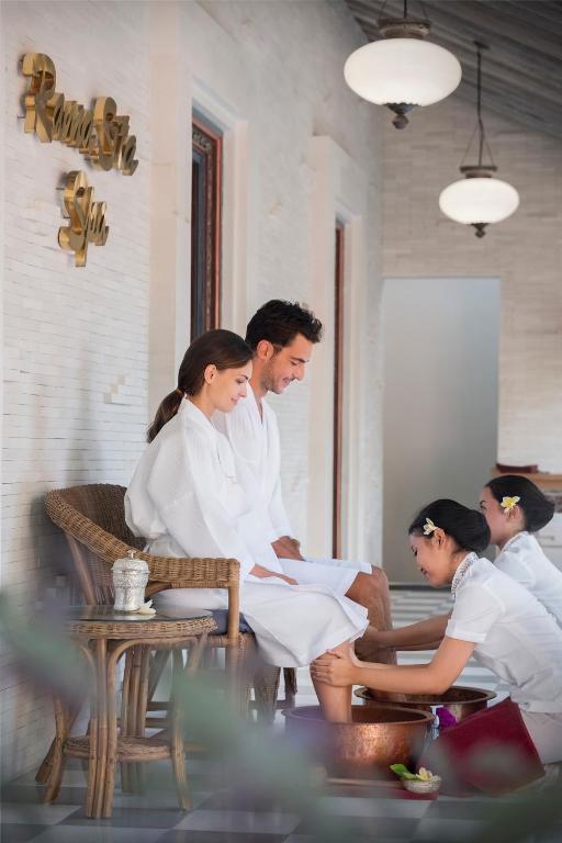 Pāris izbauda relaksējošu spa procedūru, kamēr masieres sniedz kāju kopšanas pakalpojumus, radot mierīgu un komfortablu atmosfēru.