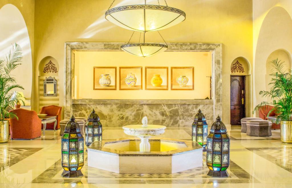 Elegants viesnīcas vestibils ar mūsdienīgu dizainu, apgaismots ar lustrām un dekorēts ar krāsainām lampām un mākslas darbiem. Iekšējā telpā ir atpūtas zona un augi, radot patīkamu atmosfēru.