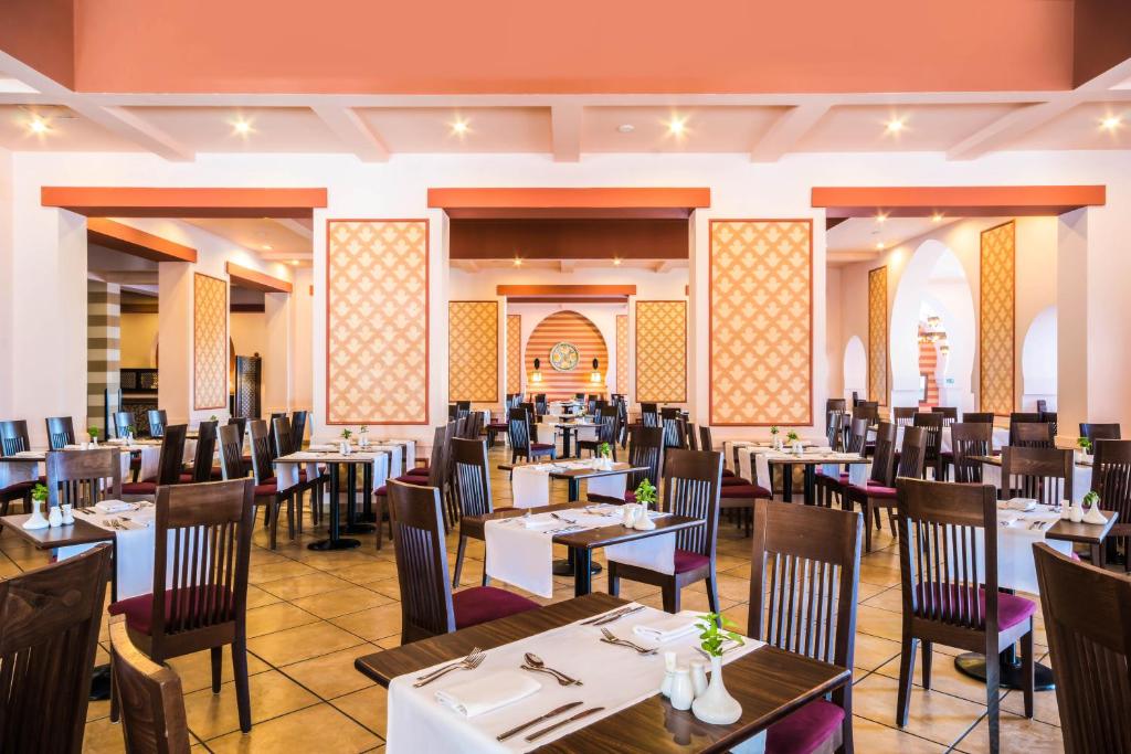 Plaša un elegantā restorāna iekārtojums ar koka galdiem un krēsliem, dekoratīviem paneļiem uz sienām un patīkamu apgaismojumu. Telpa ir kārtīgi sakārtota un gaida viesus.
