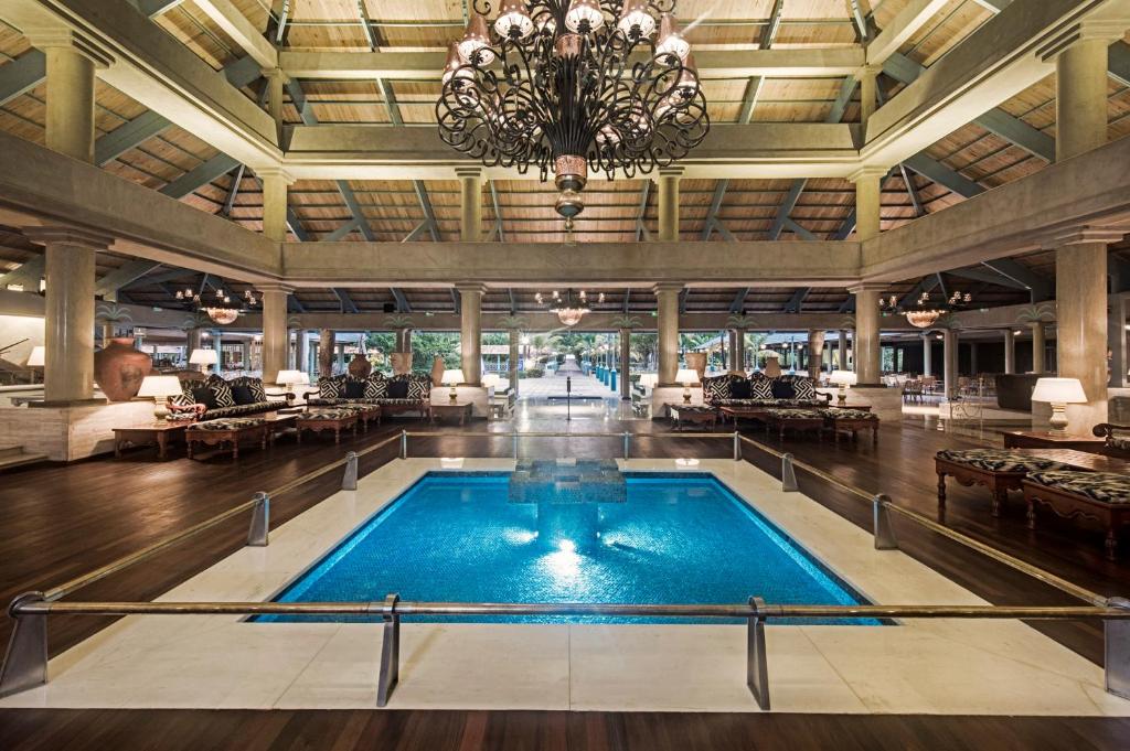 Greznas viesnīcas halles interjers ar elegantu baseinu, kas izceļas ar modernu arhitektūru un lielisku apgaismojumu. Lielas logu ailes nodrošina dabīgu gaismu un skatu uz ārējo vidi.
