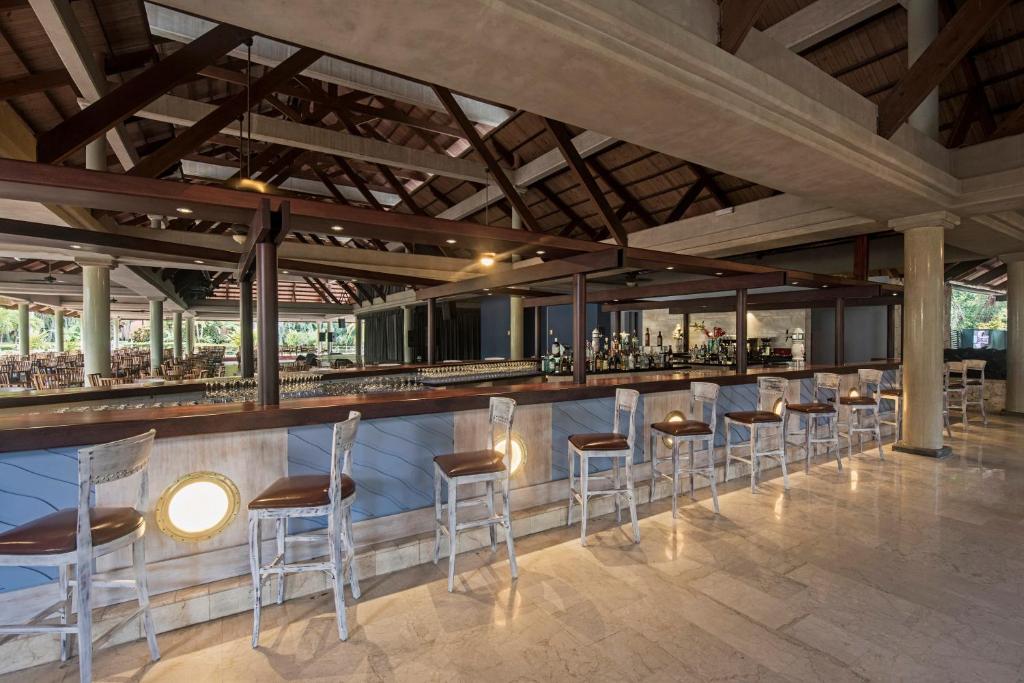 Skaists bārs ar koka jumtu un elegantiem krēsliem, kas gaida klientus. Vides dizains rada relaksējošu atmosfēru, ideālu atpūtai un izklaidei.