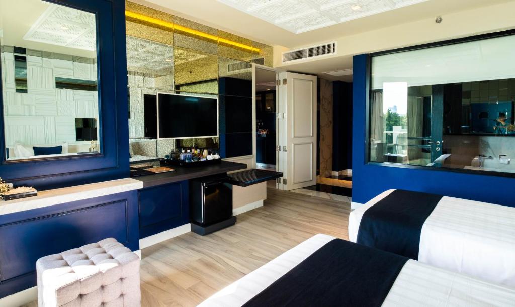 Mūsdienīgs viesnīcas numurs ar divām gultām, elegantu interjeru un lielu spoguli. Redzama TV un mini ledusskapis, kā arī plaša un gaiša telpa ar lieliem logiem.